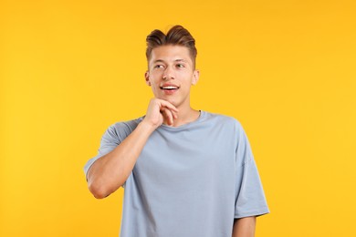 Photo of Dream come true. Positive young man thinking about something on yellow background
