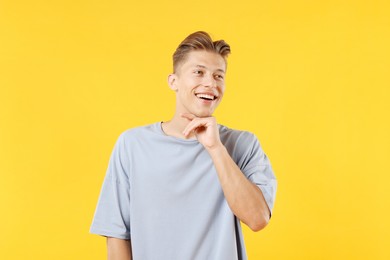 Photo of Dream come true. Positive young man thinking about something on yellow background
