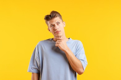 Photo of Dream come true. Positive young man thinking about something on yellow background