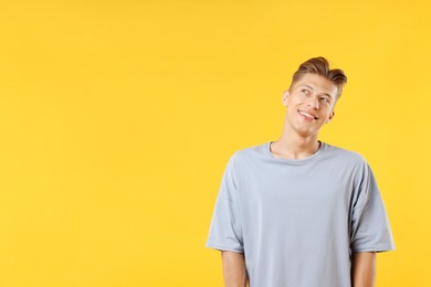 Photo of Dream come true. Positive young man thinking about something on yellow background. Space for text