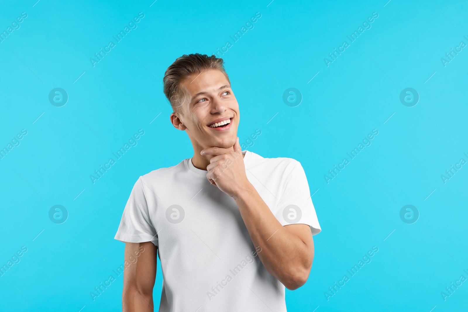Dream come true. Positive young man wishing for something on light blue background Photo of Dream come true. Positive young man wishing for something on light blue background