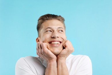 Photo of Dream come true. Positive young man wishing for something on light blue background