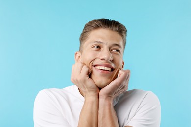 Photo of Dream come true. Positive young man wishing for something on light blue background