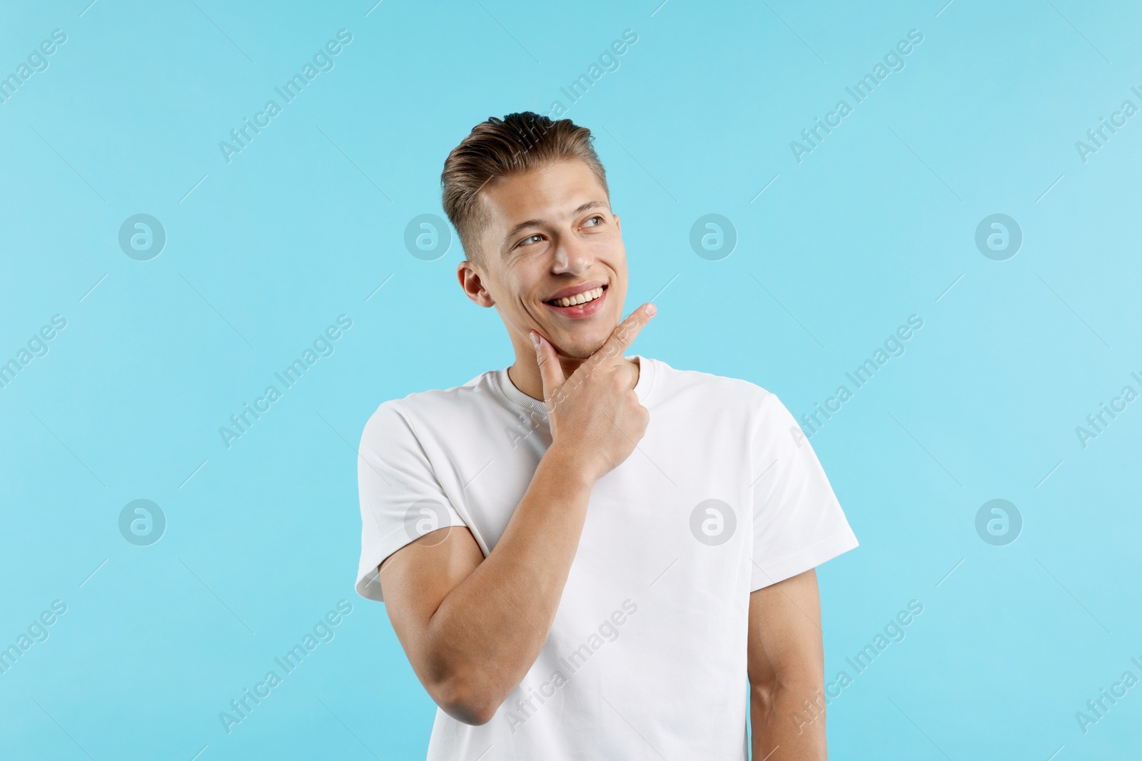 Dream come true. Positive young man wishing for something on light blue background Photo of Dream come true. Positive young man wishing for something on light blue background