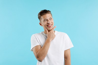 Photo of Dream come true. Positive young man wishing for something on light blue background
