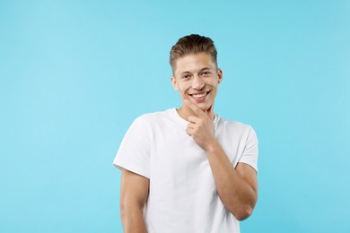 Photo of Dream come true. Positive young man wishing for something on light blue background