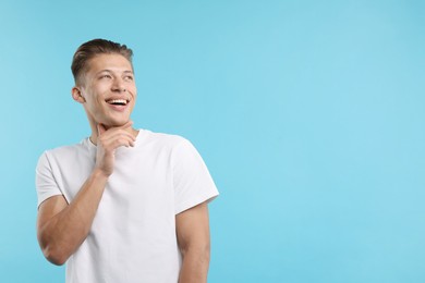 Photo of Dream come true. Positive young man wishing for something on light blue background. Space for text
