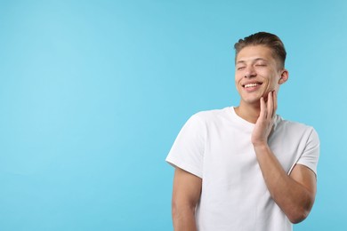 Photo of Dream come true. Positive young man wishing for something on light blue background. Space for text