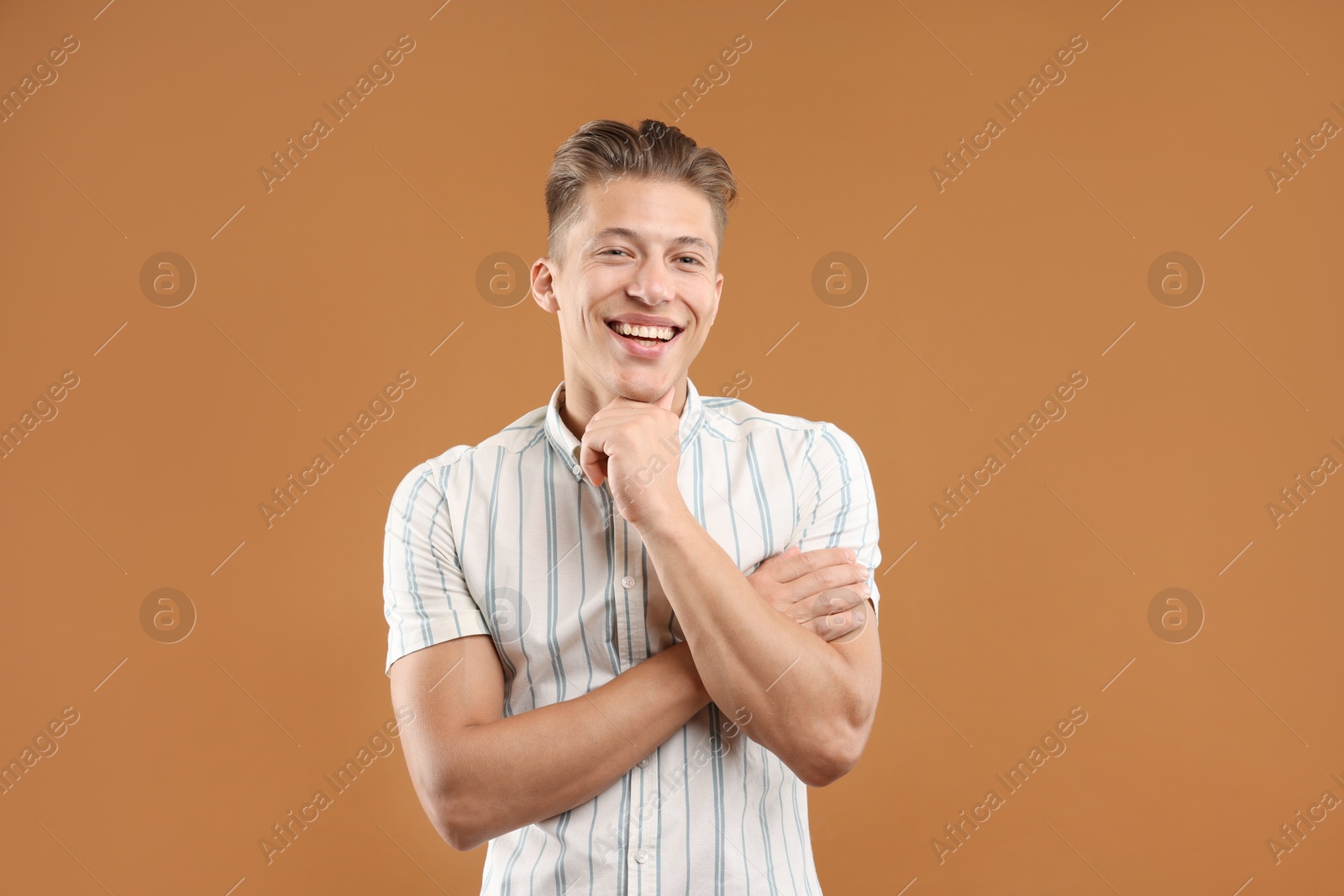 Dream come true. Positive young man thinking about something on brown background Photo of Dream come true. Positive young man thinking about something on brown background