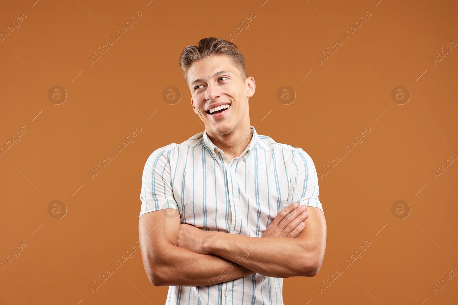 Dream come true. Positive young man thinking about something on brown background Photo of Dream come true. Positive young man thinking about something on brown background