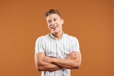 Photo of Dream come true. Positive young man thinking about something on brown background