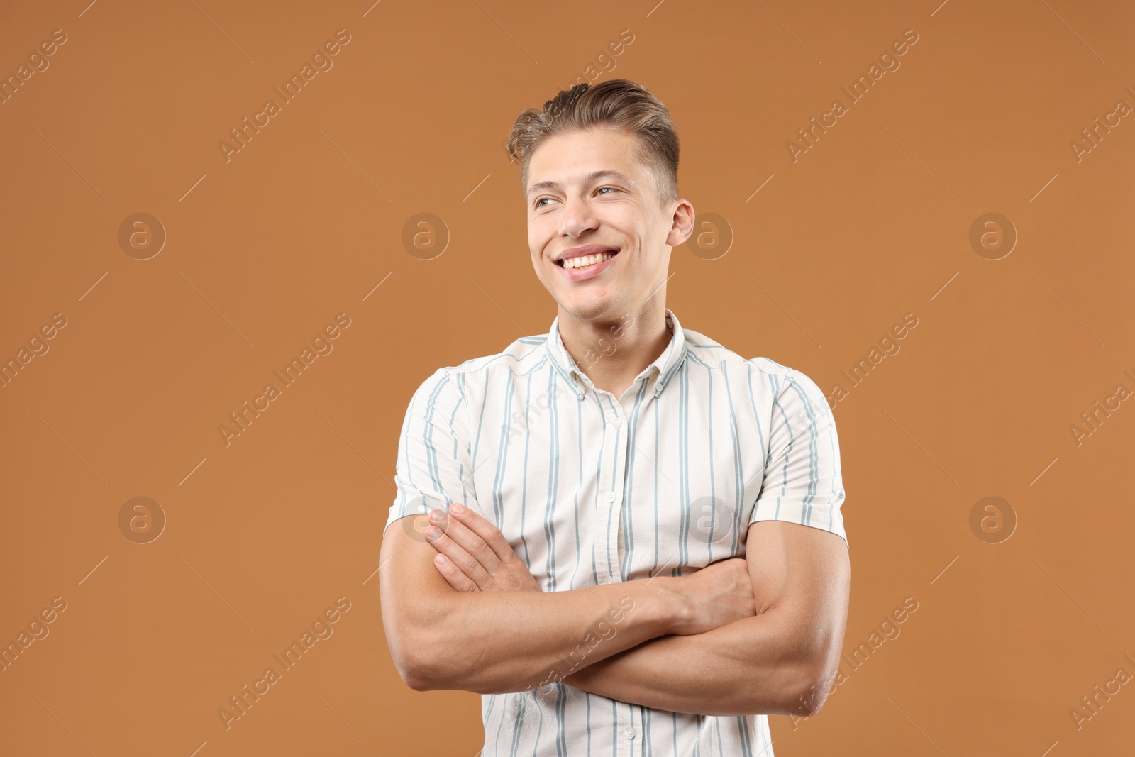 Dream come true. Positive young man thinking about something on brown background Photo of Dream come true. Positive young man thinking about something on brown background