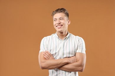 Photo of Dream come true. Positive young man thinking about something on brown background