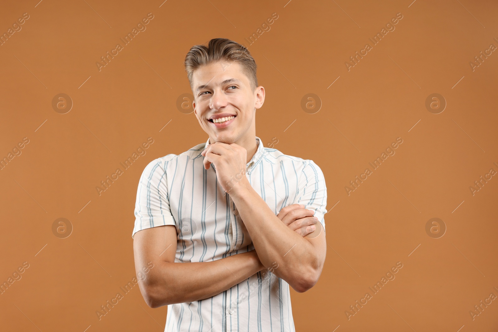 Dream come true. Positive young man thinking about something on brown background Photo of Dream come true. Positive young man thinking about something on brown background