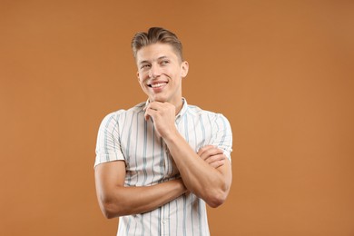 Photo of Dream come true. Positive young man thinking about something on brown background
