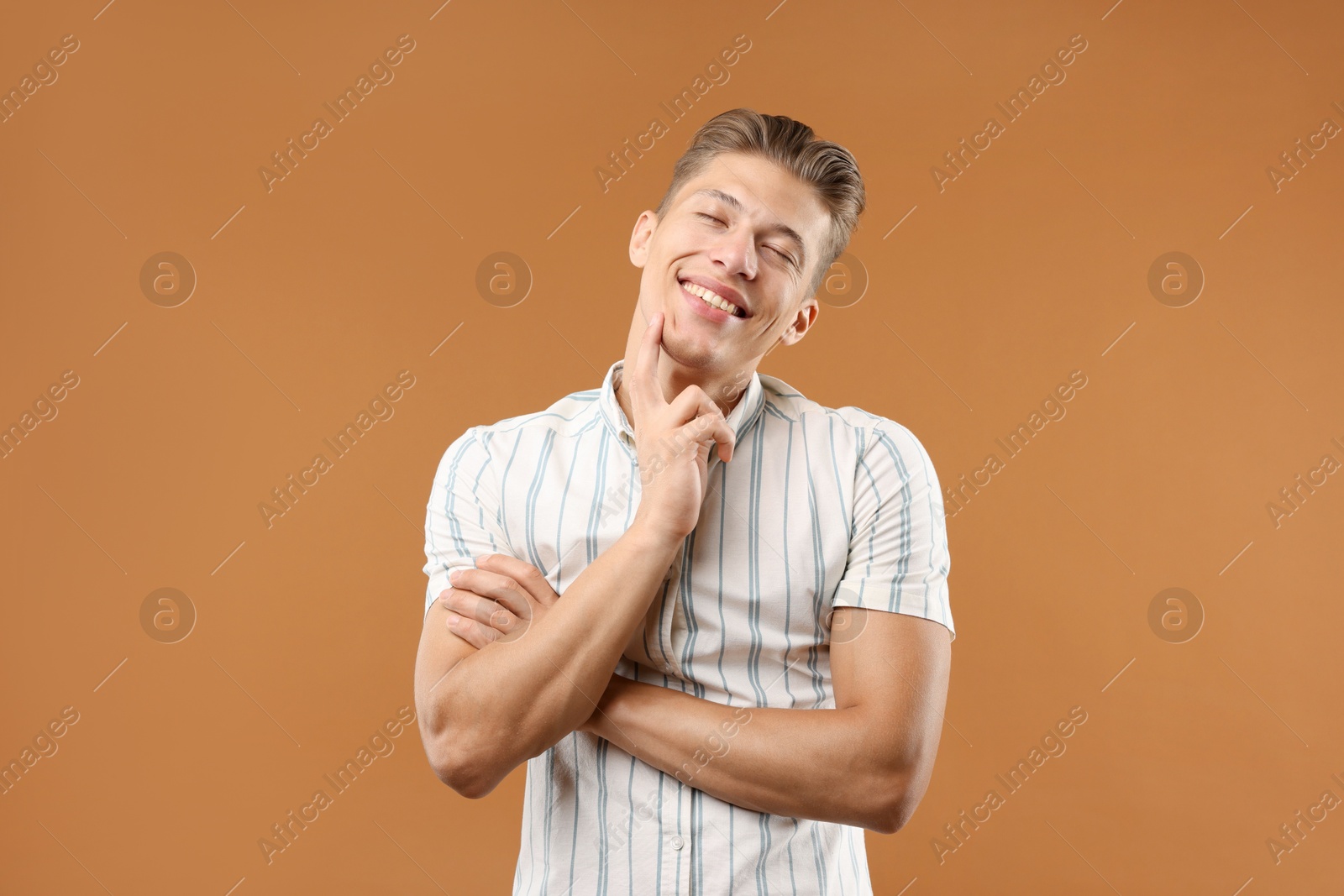 Dream come true. Positive young man thinking about something on brown background Photo of Dream come true. Positive young man thinking about something on brown background