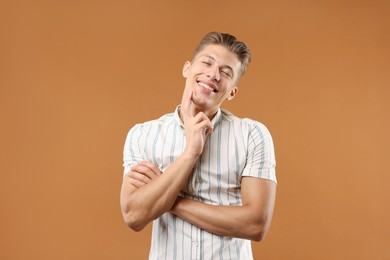 Photo of Dream come true. Positive young man thinking about something on brown background