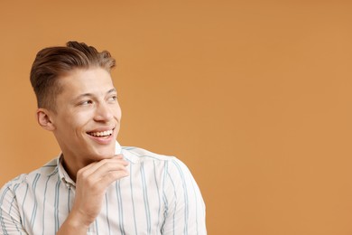 Photo of Dream come true. Positive young man thinking about something on brown background. Space for text