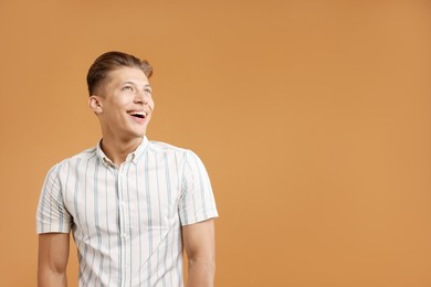 Photo of Dream come true. Positive young man thinking about something on brown background. Space for text