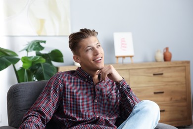 Photo of Dream come true. Positive young man thinking about something at home