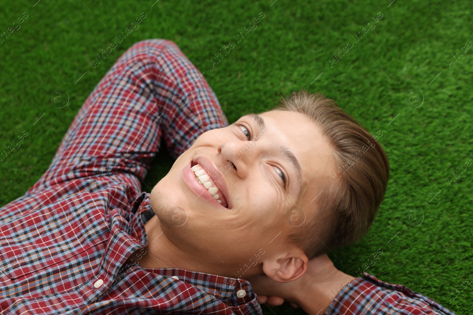 Photo of Dream come true. Positive young man thinking about something while lying on green grass