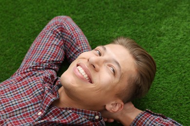 Photo of Dream come true. Positive young man thinking about something while lying on green grass