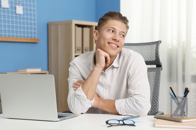 Photo of Dream come true. Positive young man thinking about something at desk indoors