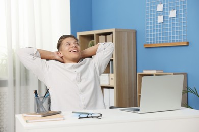 Photo of Dream come true. Positive young man thinking about something at desk indoors