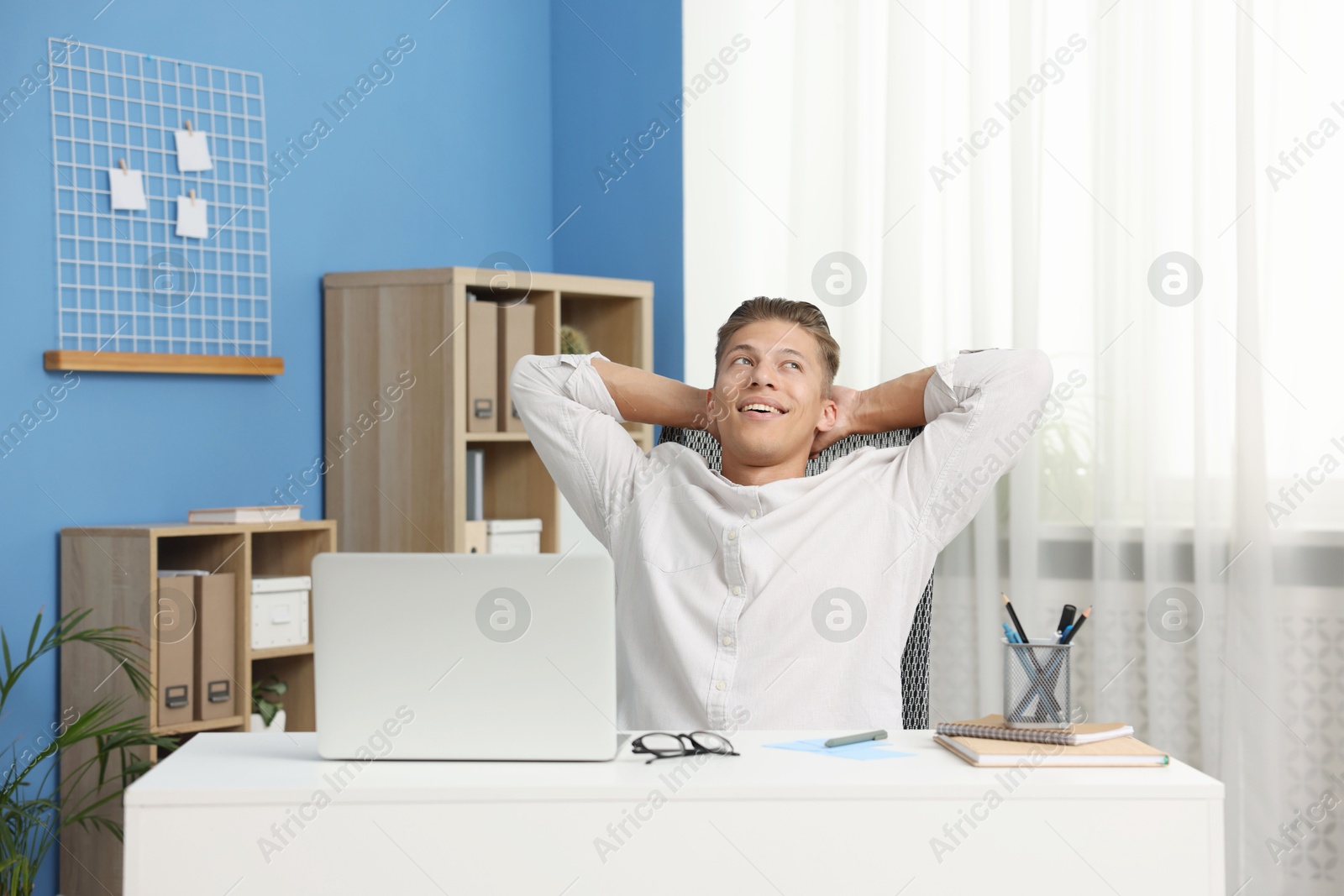 Photo of Dream come true. Positive young man thinking about something at desk indoors