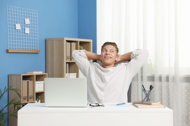 Photo of Dream come true. Positive young man thinking about something at desk indoors