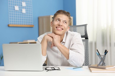 Photo of Dream come true. Positive young man thinking about something at desk indoors