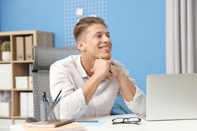 Photo of Dream come true. Positive young man thinking about something at desk indoors