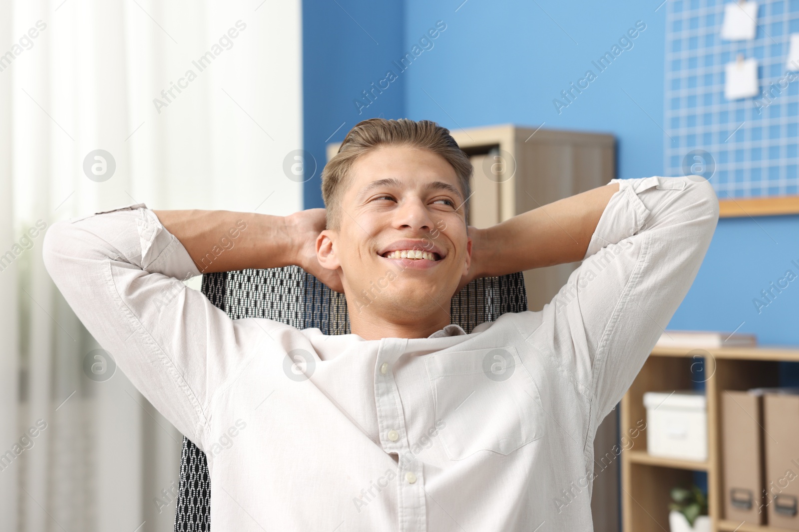 Dream come true. Positive young man thinking about something indoors Photo of Dream come true. Positive young man thinking about something indoors