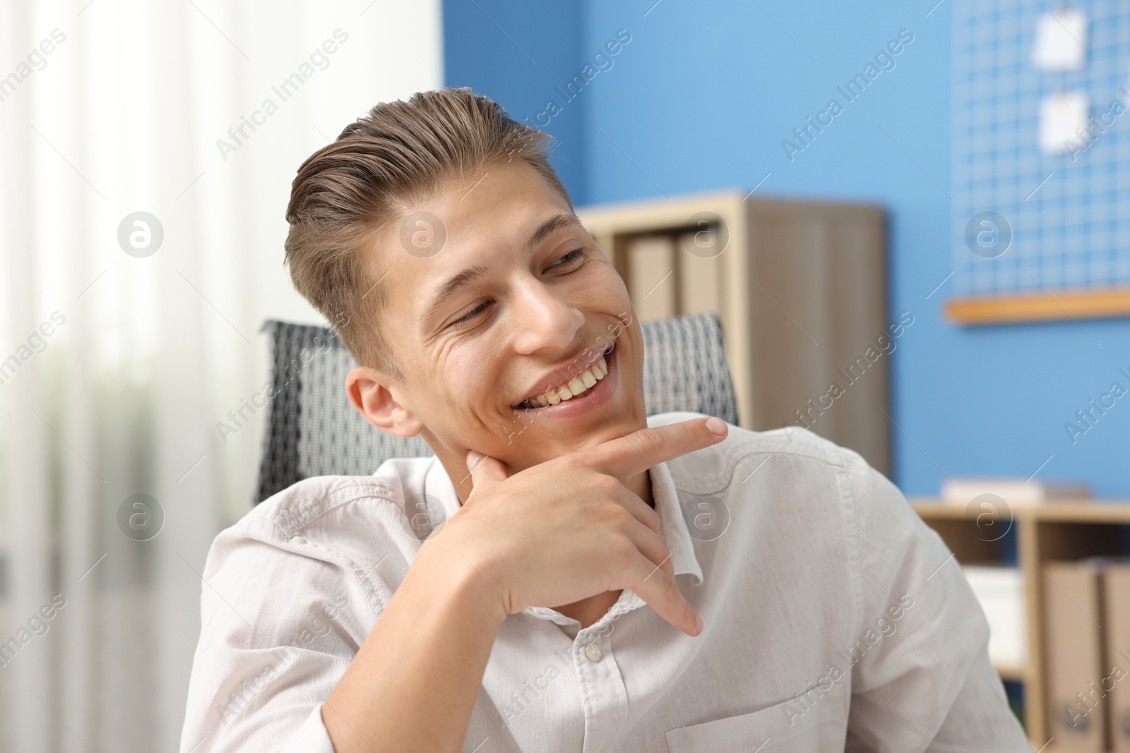 Dream come true. Positive young man thinking about something indoors Photo of Dream come true. Positive young man thinking about something indoors
