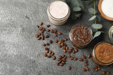Photo of Natural body scrubs in glass jars and ingredients on grey table, flat lay. Space for text