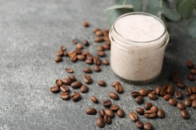 Photo of Natural body scrub in glass jar, coffee beans and eucalyptus branches, closeup. Space for text