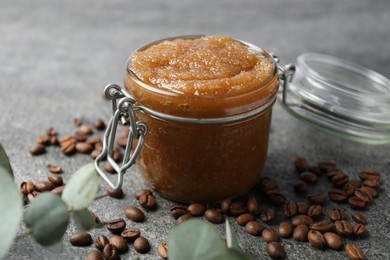 Photo of Natural body scrub in glass jar, coffee beans and eucalyptus branches, closeup