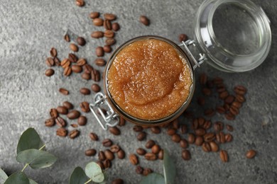 Photo of Natural body scrub in glass jar, coffee beans and eucalyptus branches, flat lay
