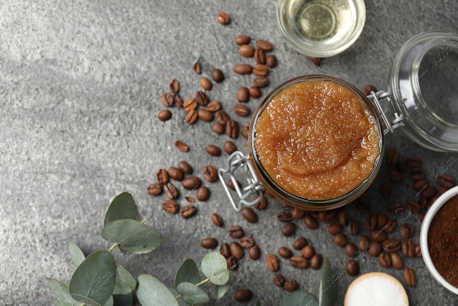 Natural body scrub in glass jar and ingredients on grey table, flat lay. Space for text Photo of Natural body scrub in glass jar and ingredients on grey table, flat lay. Space for text