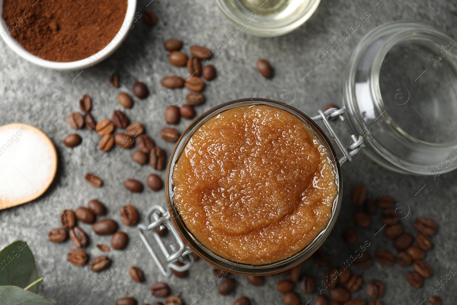 Photo of Natural body scrub in glass jar and ingredients on grey table, flat lay