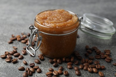 Photo of Natural body scrub in glass jar and coffee beans on grey table, closeup