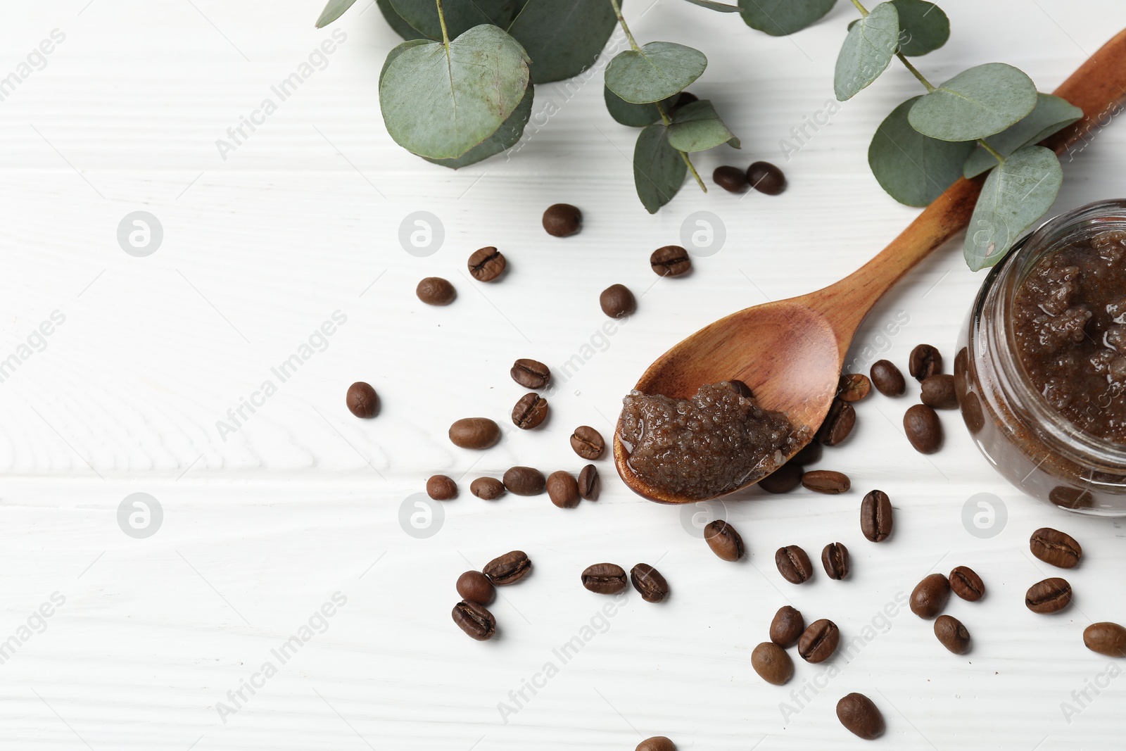 Natural body scrub, coffee beans and eucalyptus branches on white wooden table, flat lay. Space for text Photo of Natural body scrub, coffee beans and eucalyptus branches on white wooden table, flat lay. Space for text