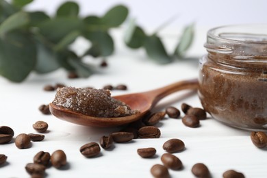 Photo of Natural body scrub, coffee beans and eucalyptus branches on white wooden table, closeup