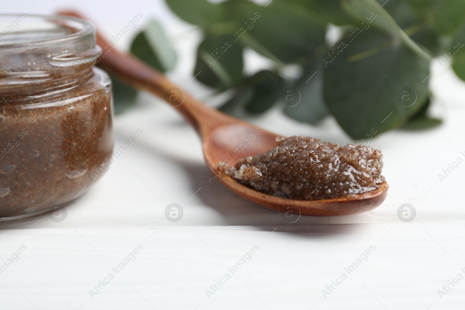 Natural body scrub, coffee beans and eucalyptus branches on white wooden table, closeup Photo of Natural body scrub, coffee beans and eucalyptus branches on white wooden table, closeup
