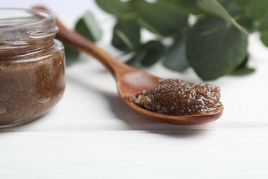 Photo of Natural body scrub, coffee beans and eucalyptus branches on white wooden table, closeup