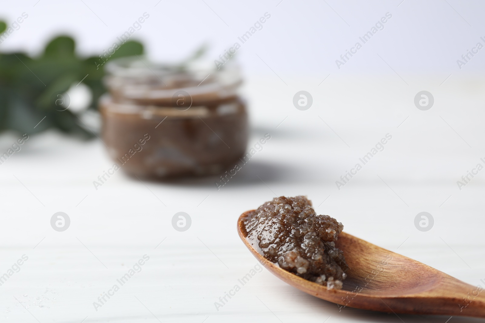 Photo of Natural body scrub in spoon on white wooden table, closeup. Space for text