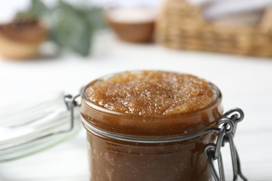 Photo of Natural body scrub in glass jar on blurred background, closeup