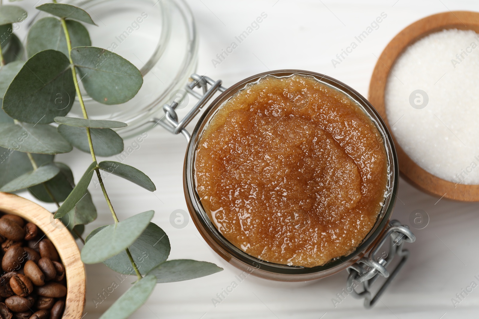Natural body scrub in glass jar and ingredients on white wooden table, flat lay Photo of Natural body scrub in glass jar and ingredients on white wooden table, flat lay