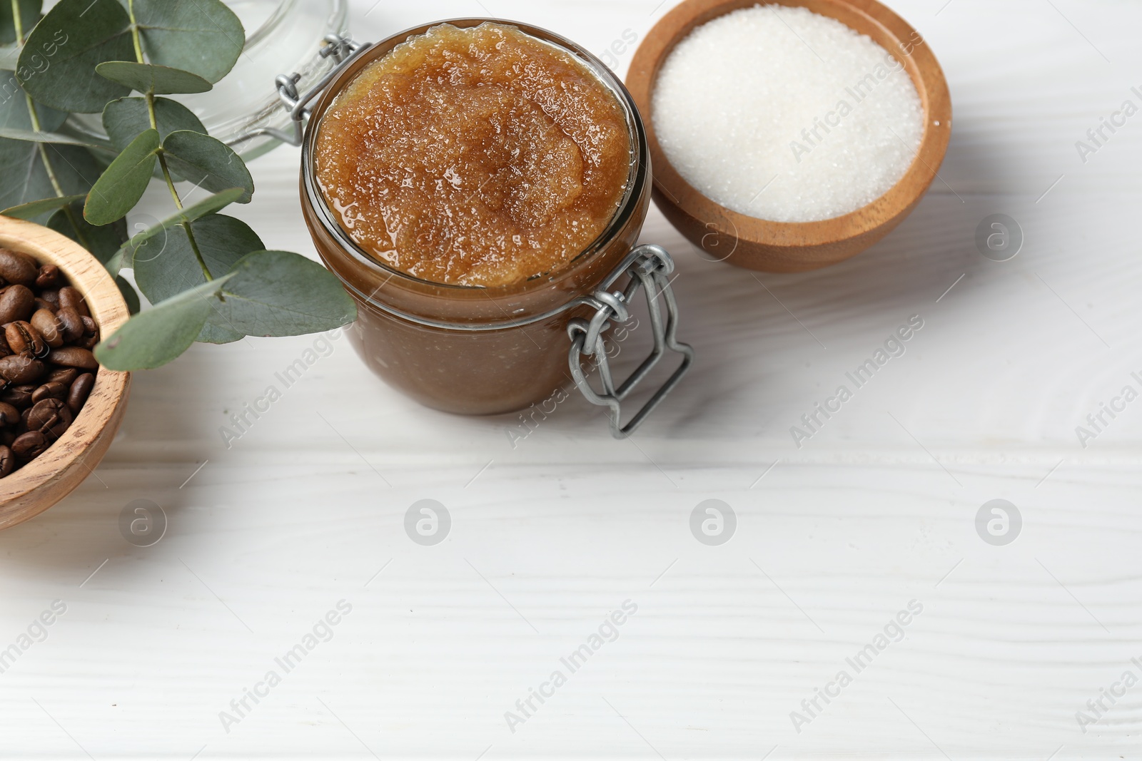 Natural body scrub in glass jar and ingredients on white wooden table, above view. Space for text Photo of Natural body scrub in glass jar and ingredients on white wooden table, above view. Space for text