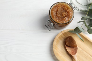 Photo of Natural body scrub and eucalyptus branches on white wooden table, flat lay. Space for text